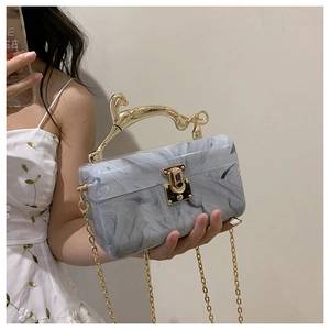 Detail of acrylic marble evening bag with gold leopard handle and chain strap