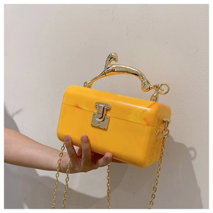 Detail of yellow acrylic marble box bag featuring a golden cheetah handle and chain strap