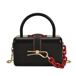 Glossy black acrylic box bag with gold bow clasp and decorative red chunky chain handle