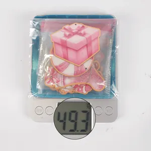 Pink Christmas wooden ornaments weighing 49.3g on a scale for festive tree DIY