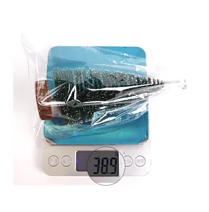 Miniature snow-dusted Christmas tree on a digital scale weighing 38.9 grams with wood base