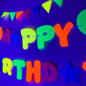 Striscione Happy Birthday neon con lettere fluorescenti, stelle e bandierine colorate