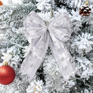 Close-up of silver mesh Christmas bow with snowflake patterns on a snowy tree