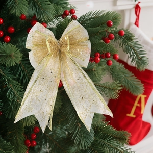 White mesh Christmas bow with gold glitter snowflakes hanging on a festive green tree
