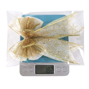 Close-up of glitter snowflake mesh Christmas bow on digital scale weighing 18.2g
