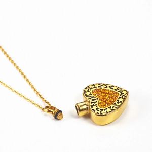 Détail du pendentif urne cœur doré avec incrustation de diamants et bouchon fileté