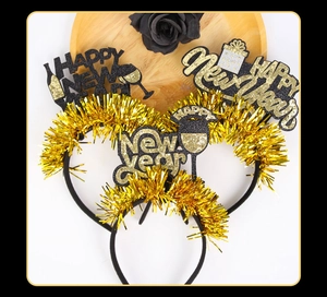 Close-up of Happy New Year headbands with gold glitter and black fringe on a wooden tray