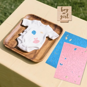 Detail of baby onesie with blue and pink gender reveal party DIY stickers on wood