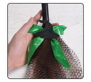 Detail of Halloween witch broom featuring green ribbon bow and black glitter hat ornament