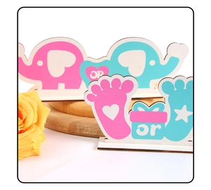 Detailed view of wood baby gender reveal party table decor with pink and blue elephant crafts