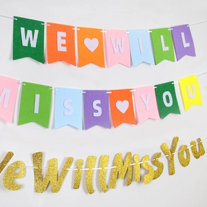 Detail of colorful felt banner and gold glitter We Will Miss You lettering party decor