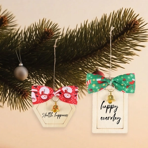 Detail of Christmas wooden tags with decorative bows and bells hanging on pine branches