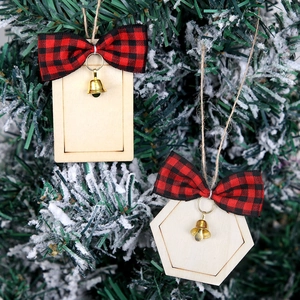 Detail of wooden Christmas ornaments with plaid bows and bells on a snowy tree