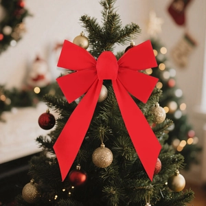 Close-up of a large red velvet Christmas bow hanging on a decorated festive pine tree