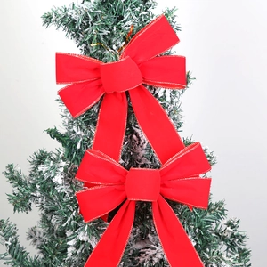 Detail of red velvet Christmas bow with gold glitter edges on a snowy pine branch