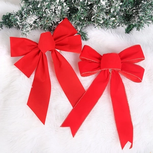 Detail of red velvet Christmas bows with gold edges on white fur background and pine needles