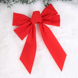 Detail of a large red velvet Christmas bow with long tails on a soft white plush background