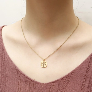 Dettaglio della collana con ciondolo Double Happiness Xi dorata su una modella