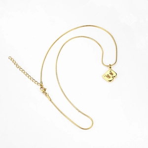 Detail of gold snake chain necklace featuring a polished capital letter B pendant