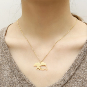 Collier minimaliste plaqué or 18 carats avec pendentif ours porté par une femme élégante