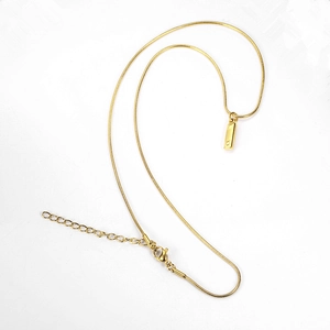 Detail of gold snake chain necklace featuring a minimalist Taurus zodiac pendant