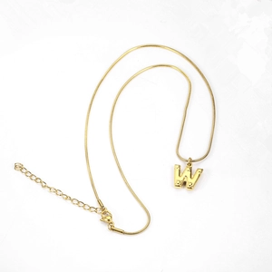 Close-up of golden letter W pendant on snake chain with textured dot design details