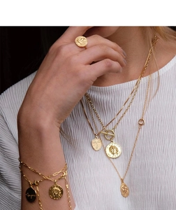Gros plan de colliers médaillons en plaqué or 18K et accessoires superposés pour femmes