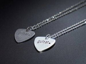 Macro view of two brushed steel guitar pick necklaces with star and guitar engraving