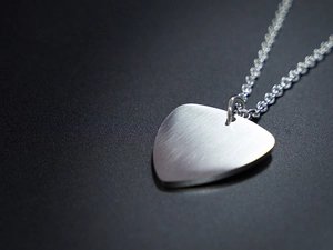 Macro shot of guitar pick pendant with brushed stainless steel texture and silver chain