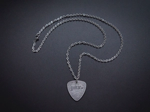 Macro shot of stainless steel guitar pick pendant with engraved text on a vintage chain