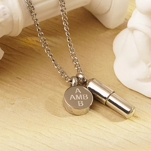 Detalle de la cápsula de plata y la placa redonda grabada en un collar con cadena tipo O
