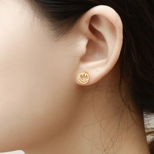 Gros plan sur un clou d'oreille sourire plaqué or 18 carats porté sur l'oreille du modèle