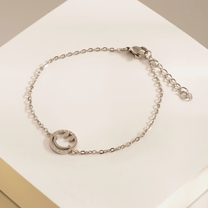 Dettaglio del bracciale argentato con faccina sorridente, chiusura a moschettone e catena