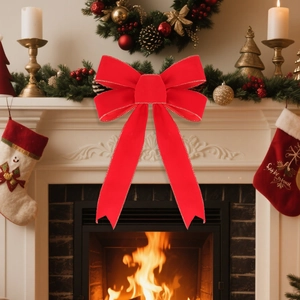 Large red velvet Christmas bow with gold trim decoration placed on a festive mantel