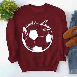 Flat lay of burgundy Game Day sweatshirt with football print, jeans, and shoes