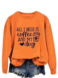 Detail of orange crewneck sweatshirt fabric showing ALL I NEED coffee and dog text