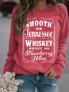 Detail shot of the white letter print on a red crewneck sweatshirt worn with jeans