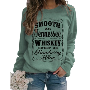 Detail of green crewneck sweatshirt featuring vintage black text and scrollwork pattern