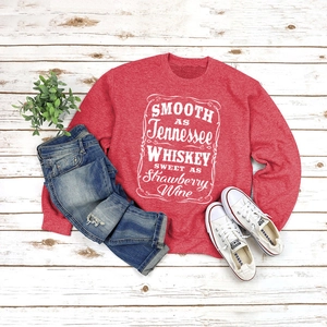 Detail of red crewneck sweatshirt with white Tennessee whiskey lettering and denim jeans