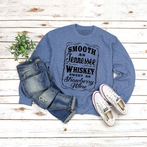 Flat lay of gray-blue sweatshirt with vintage typography paired with ripped jeans