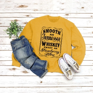 Flat lay of mustard yellow crewneck sweatshirt with vintage lettering on rustic wood floor
