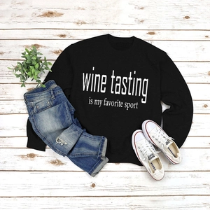 Flat lay of black crewneck sweatshirt with 'Wine Tasting' print and casual outfit details