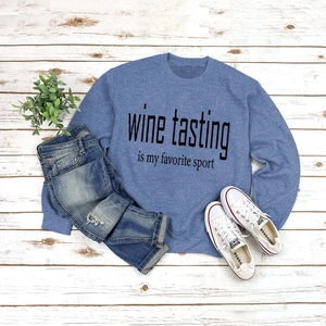 Close-up of blue long-sleeve sweatshirt with 'Wine Tasting' print on wooden floor
