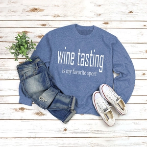 Flat lay of a blue sweatshirt with Wine Tasting text and distressed denim jeans