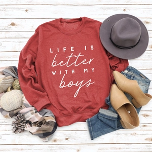 Flat lay of red crewneck sweatshirt with 'LIFE IS better WITH MY boys' print and accessories