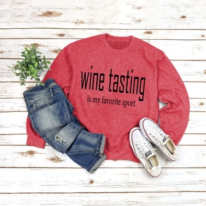 Flat lay of red crewneck sweatshirt with 'Wine Tasting' print on white wooden background