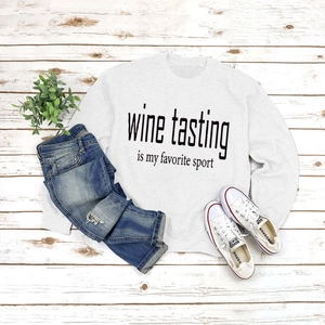 Flat lay of light grey sweatshirt with Wine Tasting slogan on rustic wood floor