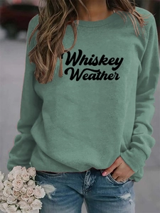 Close-up of Whiskey Weather slogan on sage green crewneck sweatshirt with knit texture
