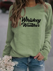Close-up of black Whiskey Weather typography print on soft grass green sweatshirt