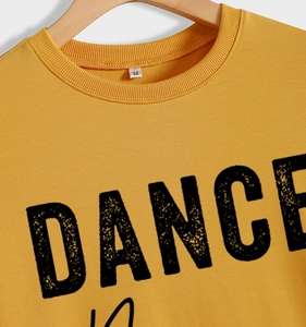 Detail of DANCE print on yellow crewneck sweatshirt with size M tag on the collar